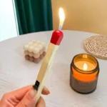 Wooden matchstick lighter with soft flame lighting a scented candle
